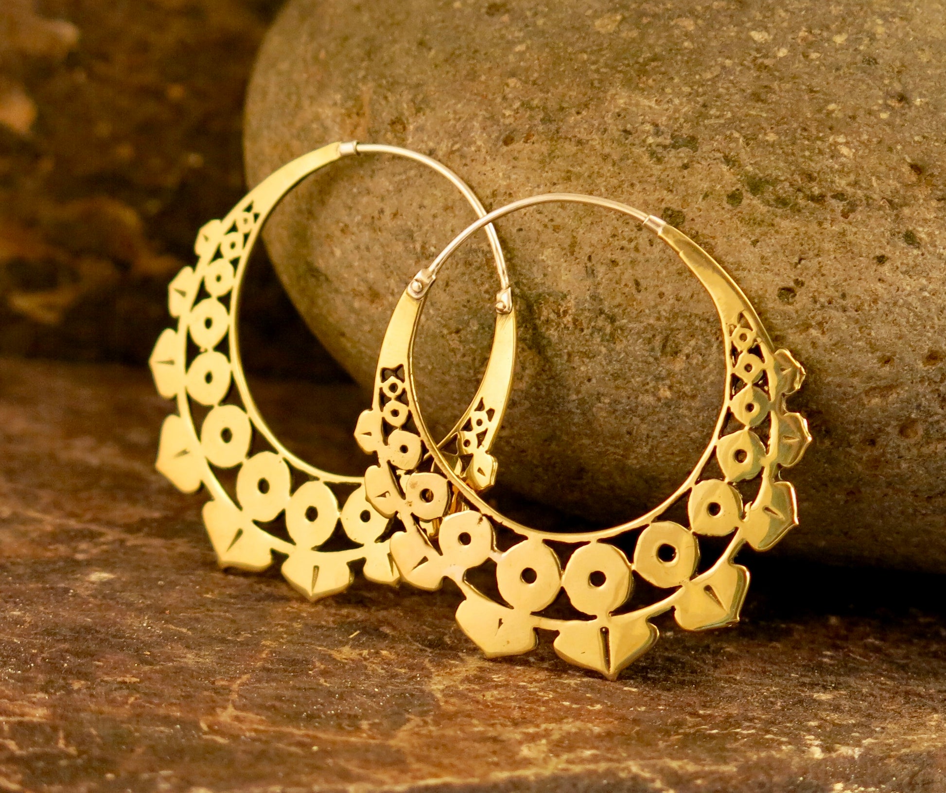 Close-up of the Lotus Geo earrings in Italian brass resting on a rustic stone backdrop, highlighting their intricate geometric lotus-inspired design.