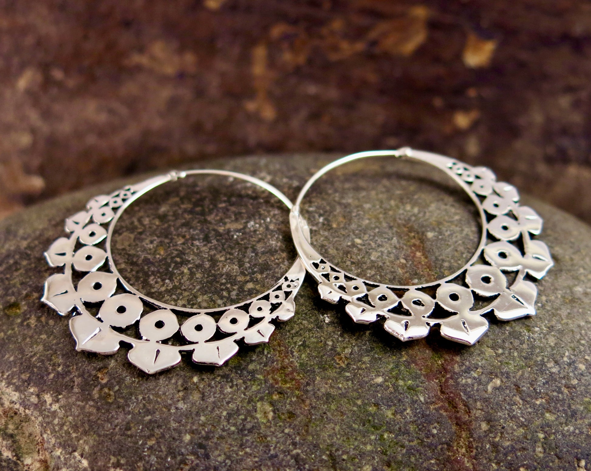 Close-up of the Lotus Geo earrings in silver plating resting on a rustic stone backdrop, highlighting their intricate geometric lotus-inspired design.