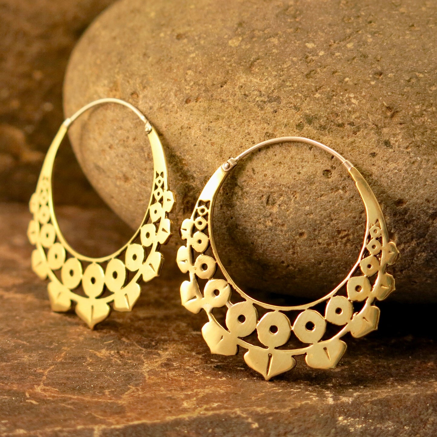 Close-up of the Lotus Geo earrings in Italian brass resting on a rustic stone backdrop, highlighting their intricate geometric lotus-inspired design.